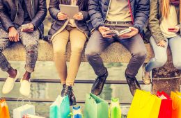 People sitting in a row with shopping bags