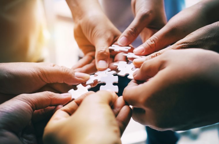 People connecting parts of a jigsaw.