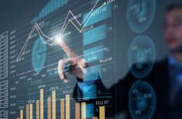 Businessman pointing at a screen of charts and graphs.